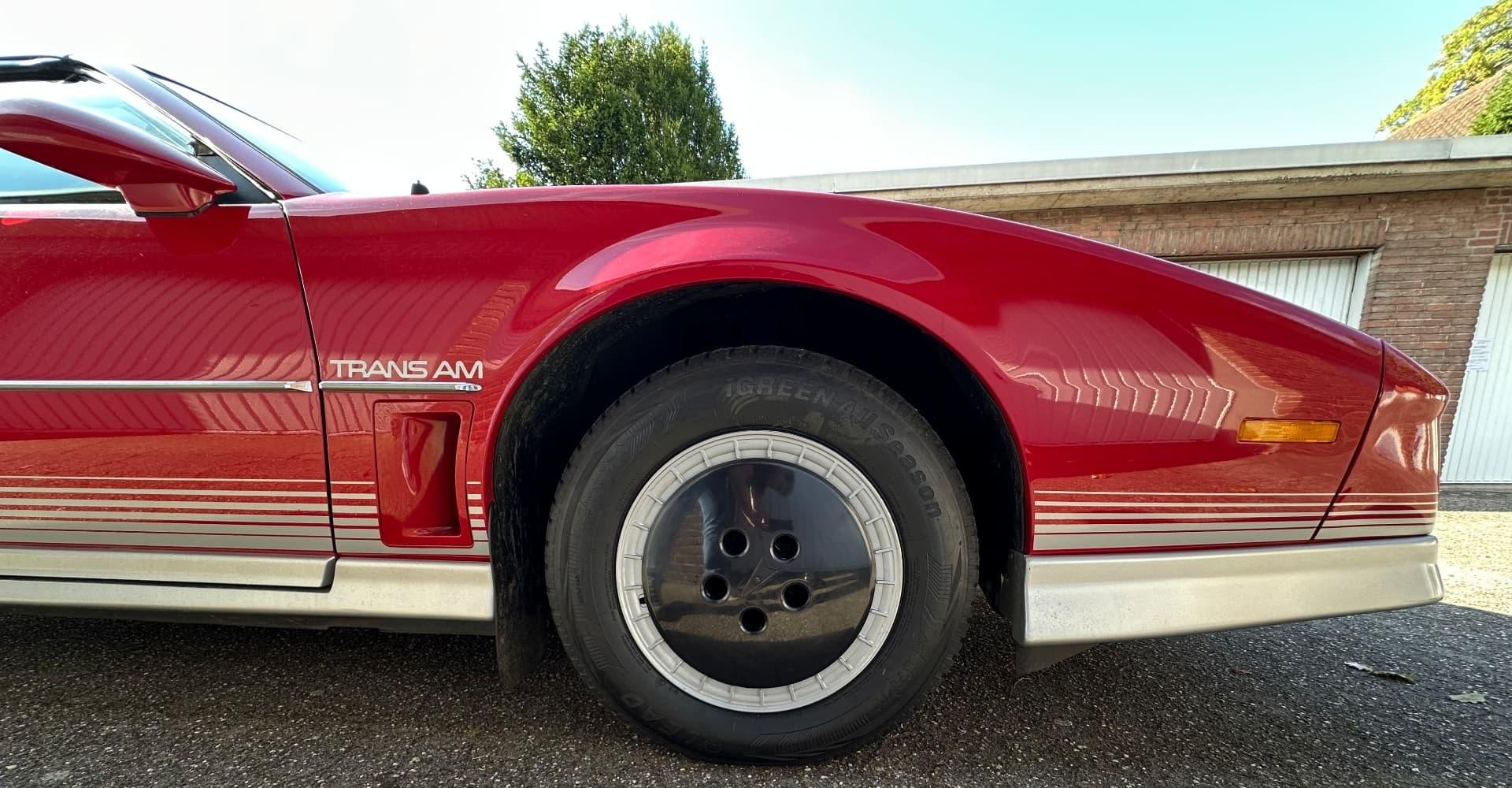 Seitenansicht des montierten schwarzen Bowling Ball Hubcaps am roten Pontiac Trans Am
