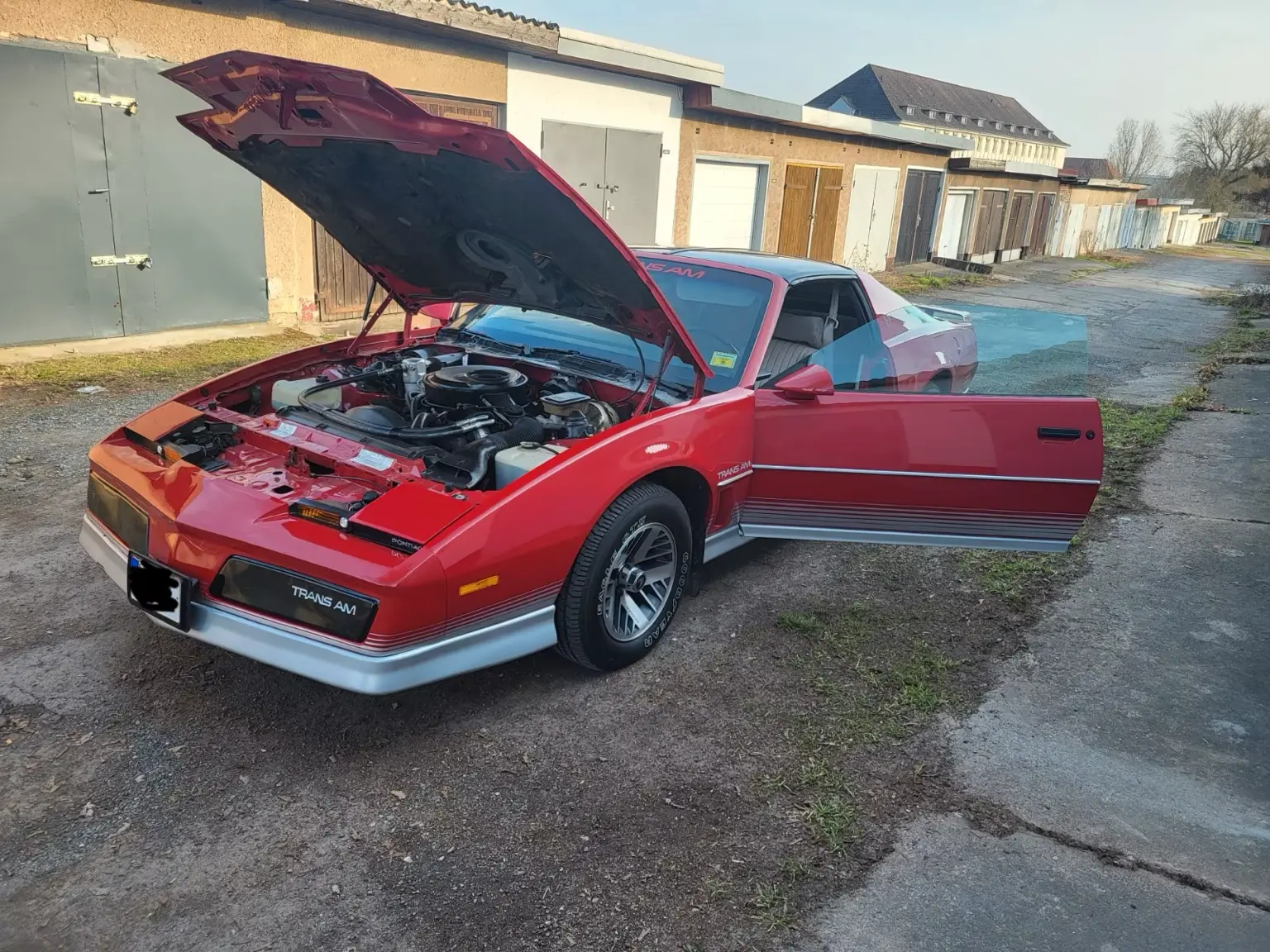 Roter Pontiac Trans Am mit geöffneter Motorhaube und sichtbarem V8-Motorraum