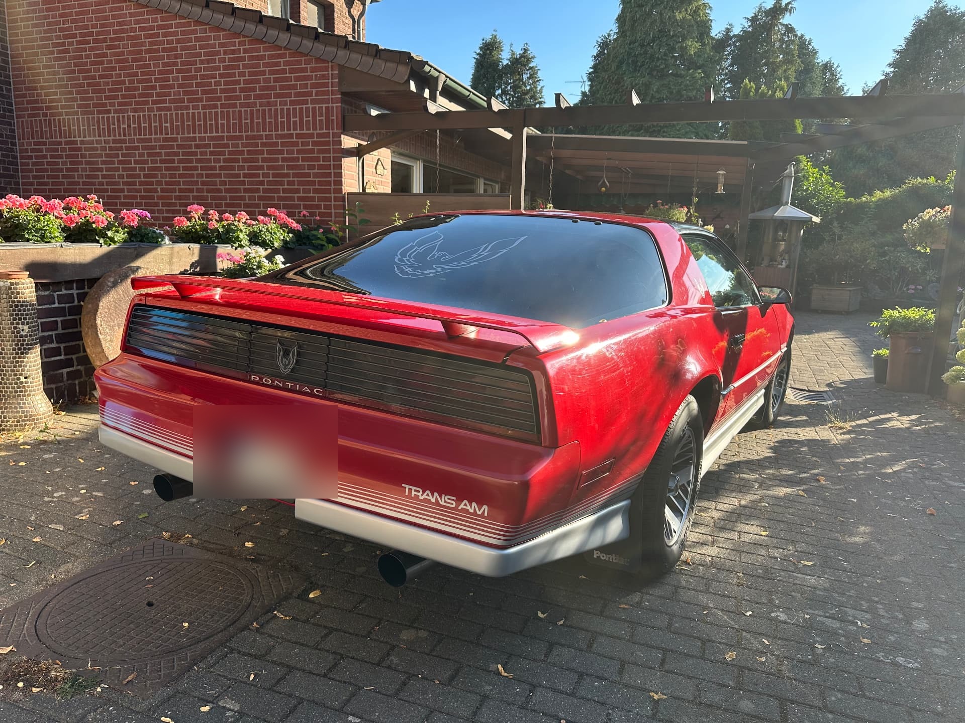 Schräge Heckansicht eines roten Pontiac Firebird Trans Am mit Heckspoiler