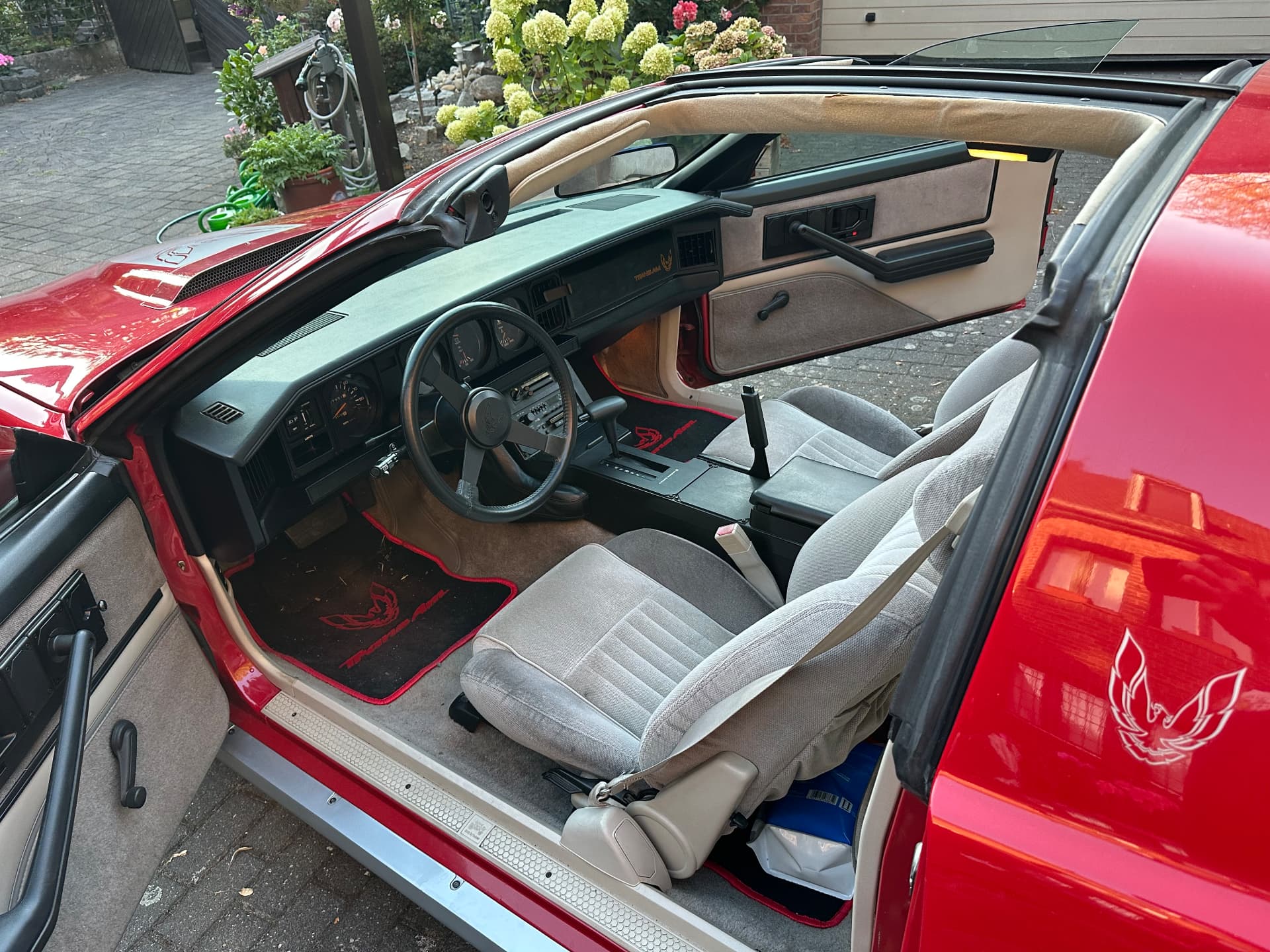 Innenraum eines Pontiac Trans Am mit grauen Velourssitzen, schwarzem Armaturenbrett und geöffnetem T-Top